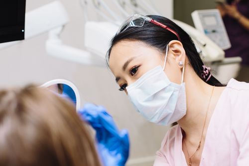Free Asian female dentist working with a patient in a dental clinic, focusing on oral hygiene. Stock Photo