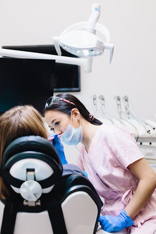 Free Dentist at Work Examining the Teeth of a Patient Stock Photo