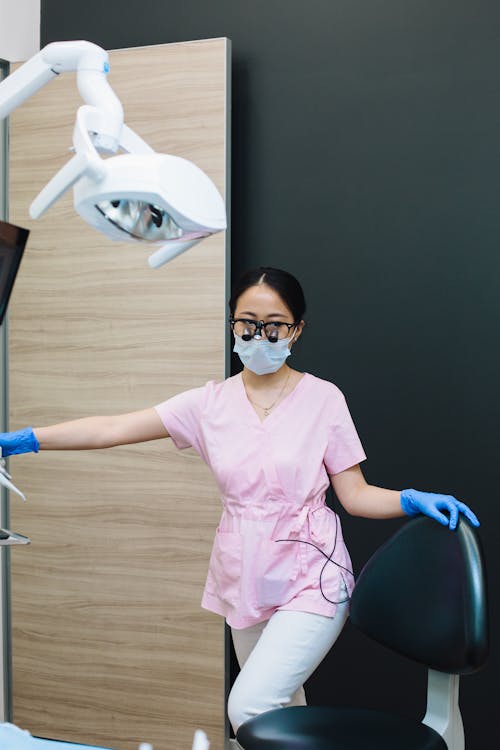 Woman in Pink Scrubs and Blue Latex Gloves Wearing Black Sunglasses with Magnifier
