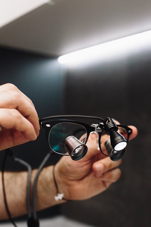 Person Holding Black Framed Eyeglasses with Loupe