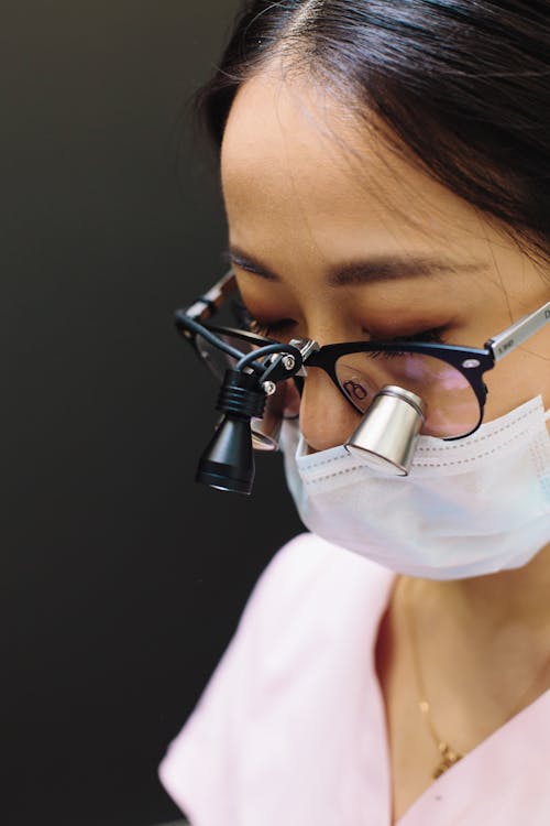 Woman With White Face Mask Wearing Eyeglasses With Loupe