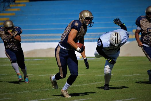 Players in action during a competitive football game on the field, showcasing teamwork and athleticism.