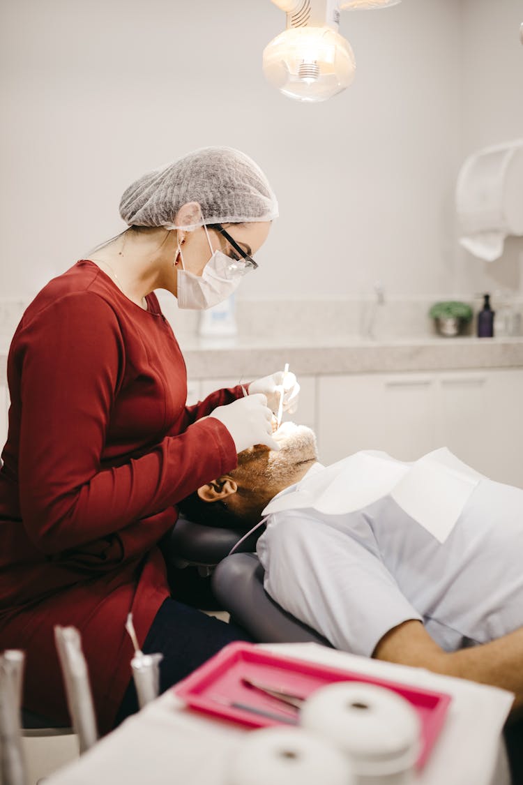 Unrecognizable Dentist In Mask Examining Teeth Of Patient