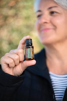 Senior woman smiling and holding a doTERRA fennel essential oil bottle, showcasing natural healing.