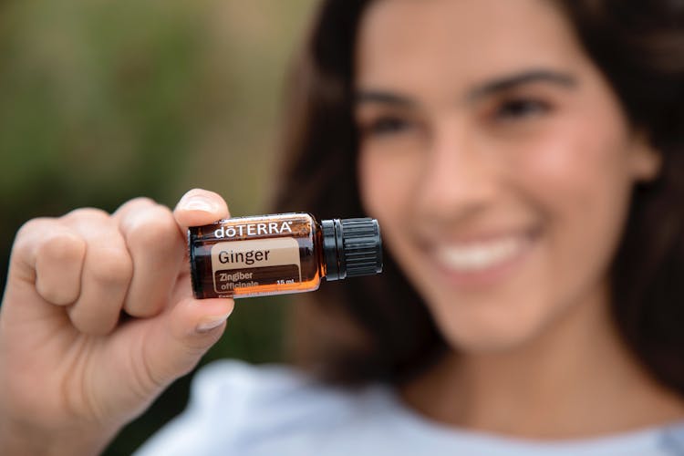 A Woman Holding A Doterra Ginger Essential Oil