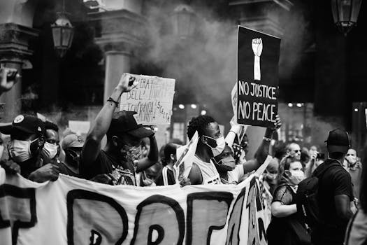 Black and white photo of a protest in Torino with people holding placards and wearing masks.