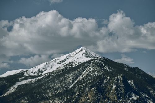 Free Scenic view of a snow-capped mountain peak under white clouds in Colorado, USA. Stock Photo