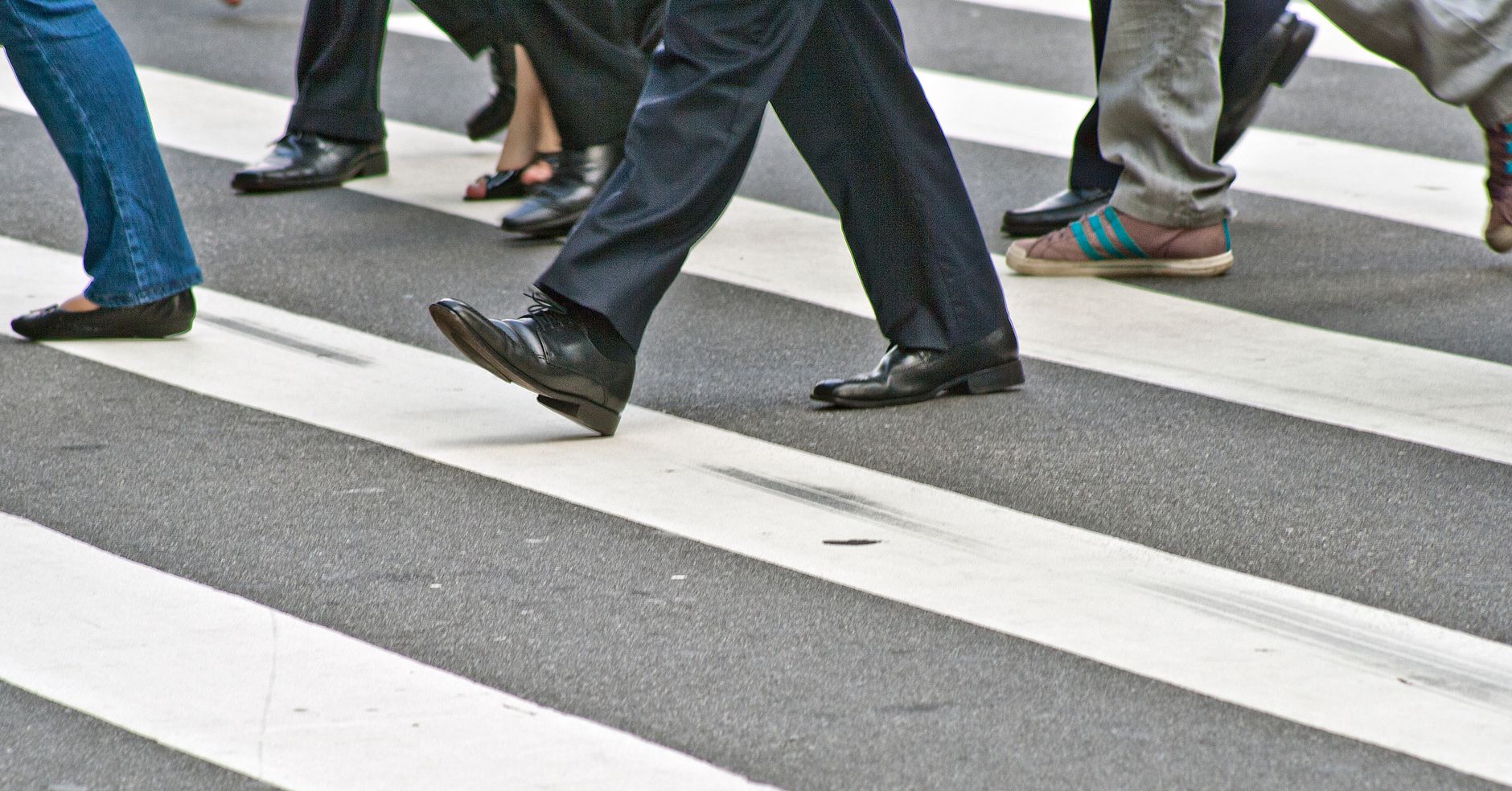 A diverse group of people crossing the street on a zebra pedestrian crossing in a city.