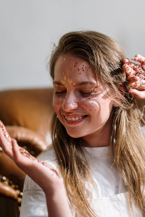 Woman in White Crew Neck T-shirt With Red Powder on Her Face