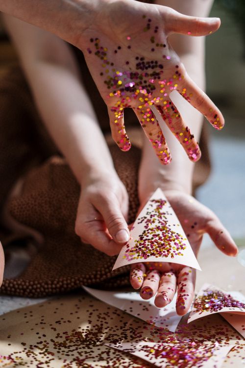 Free Hands engaging in a colorful glitter DIY craft project creating sparkly decorations. Stock Photo