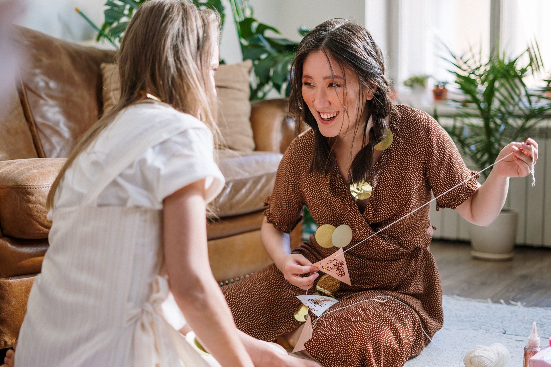 Two women enjoying a creative DIY project indoors with handmade decorations.