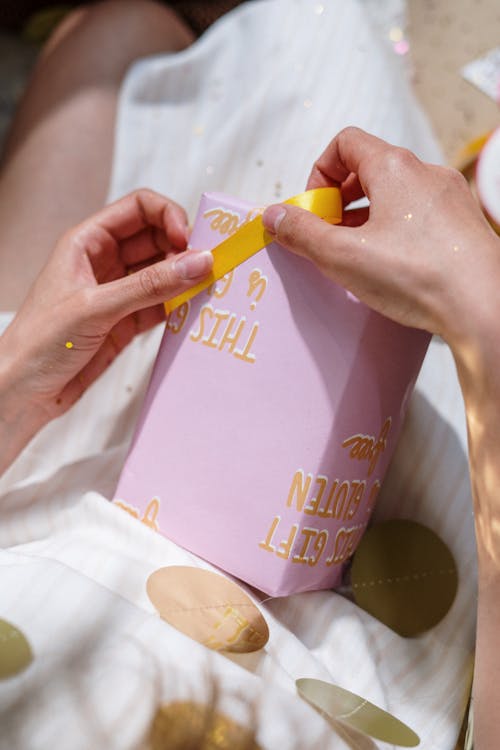 Person Holding Yellow and Pink Labeled Bottle