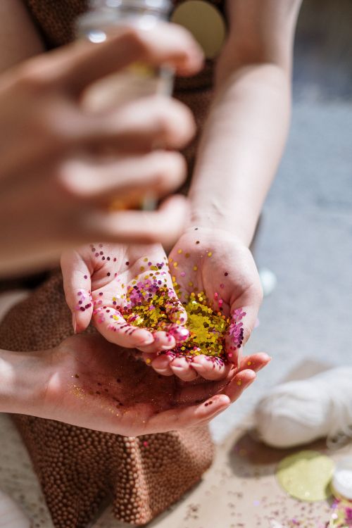 Free A close-up of hands holding vibrant glitter and confetti, showcasing creativity and DIY spirit. Stock Photo