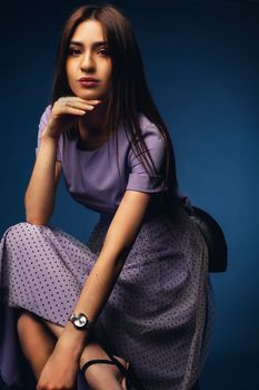 Portrait of a woman in a lavender dress against a dark background, exuding elegance.