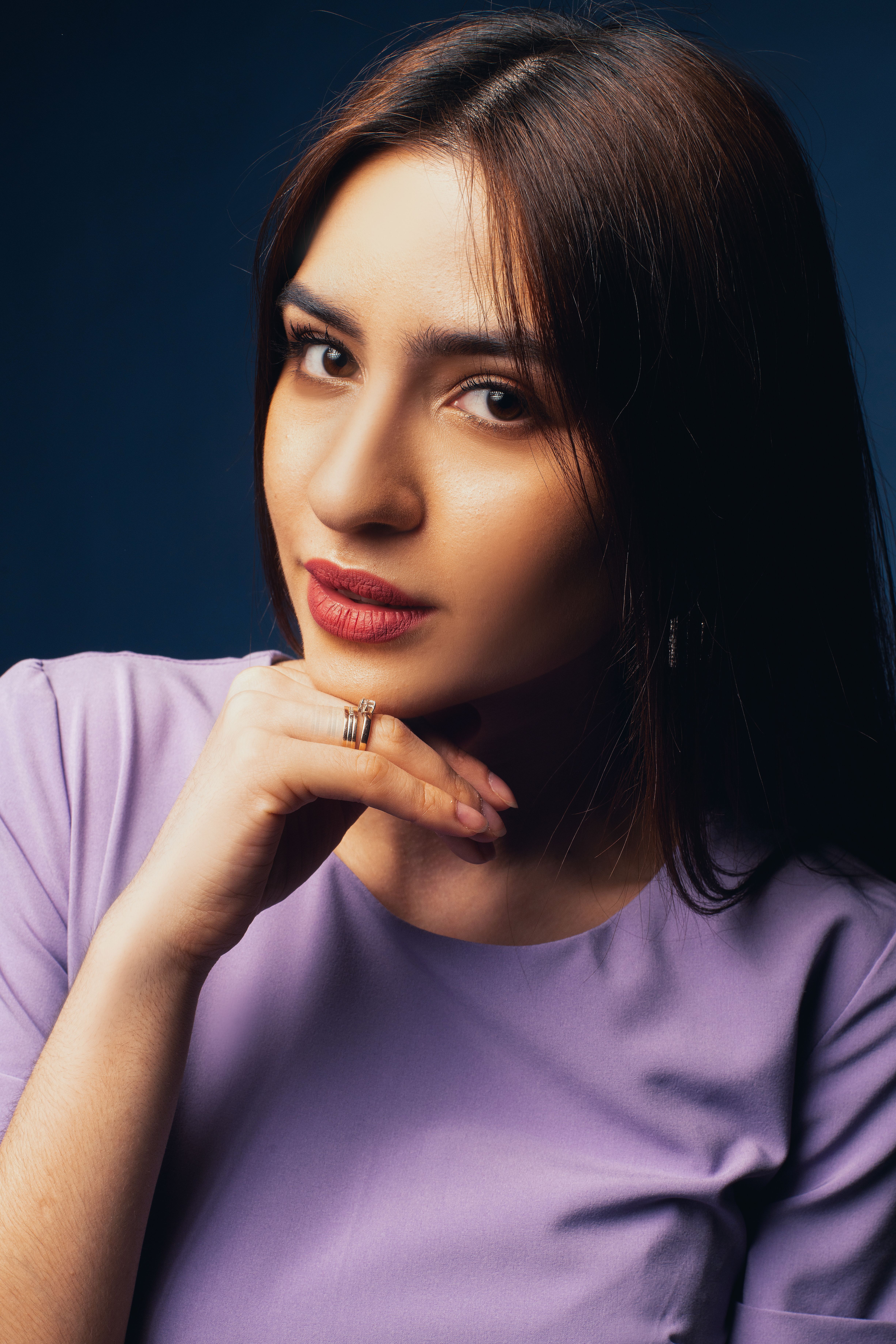 Close-up portrait of an elegant woman in a lavender dress with a thoughtful pose.