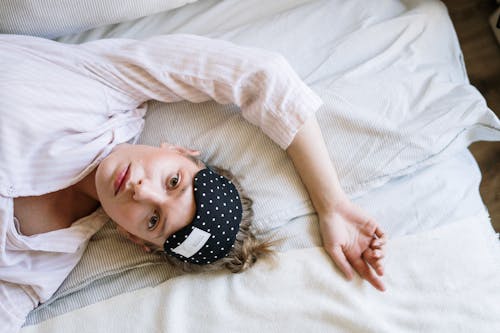 Free Woman in White Crew Neck T-shirt Lying on Bed Stock Photo