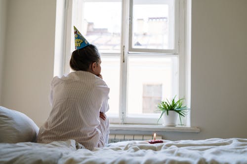 Free Woman in White Long Sleeve Shirt Sitting on Bed Stock Photo