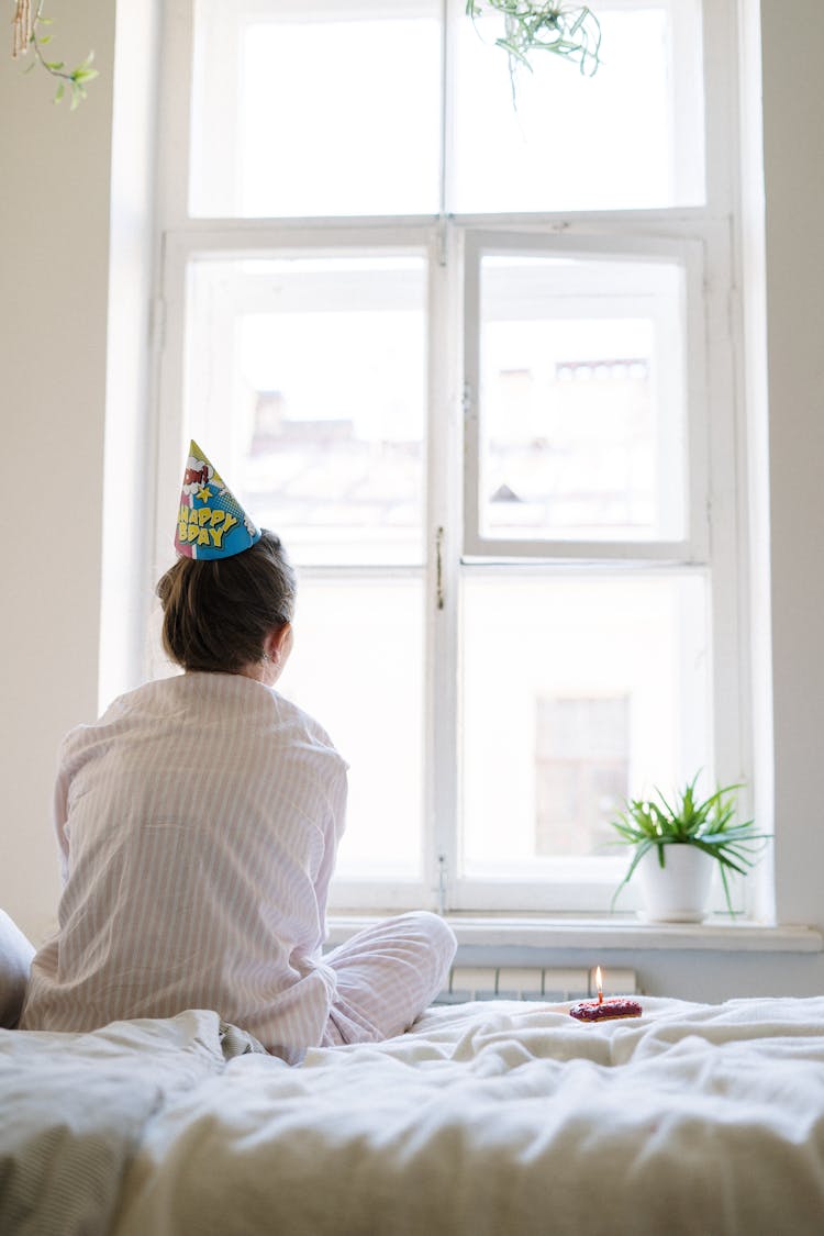 Woman In White Long Sleeve Shirt Sitting On Bed