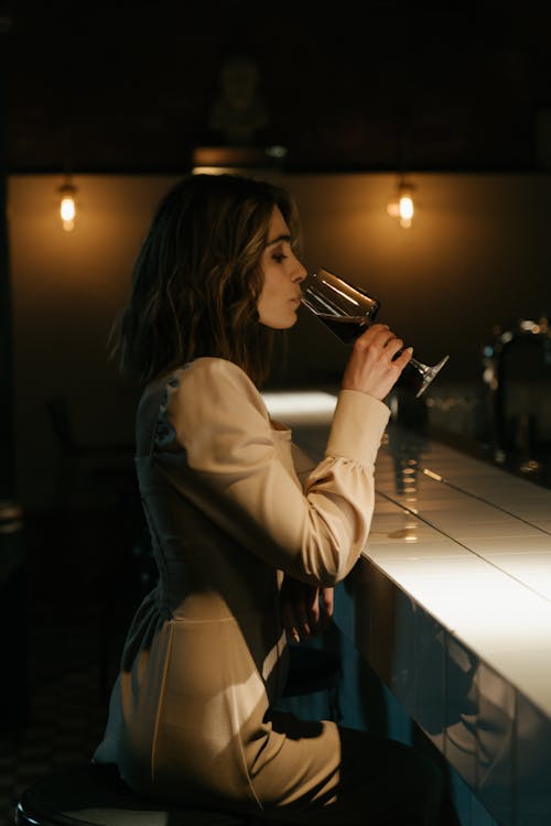 Free Woman in White Long Sleeve Shirt Drinking from a Glass Stock Photo