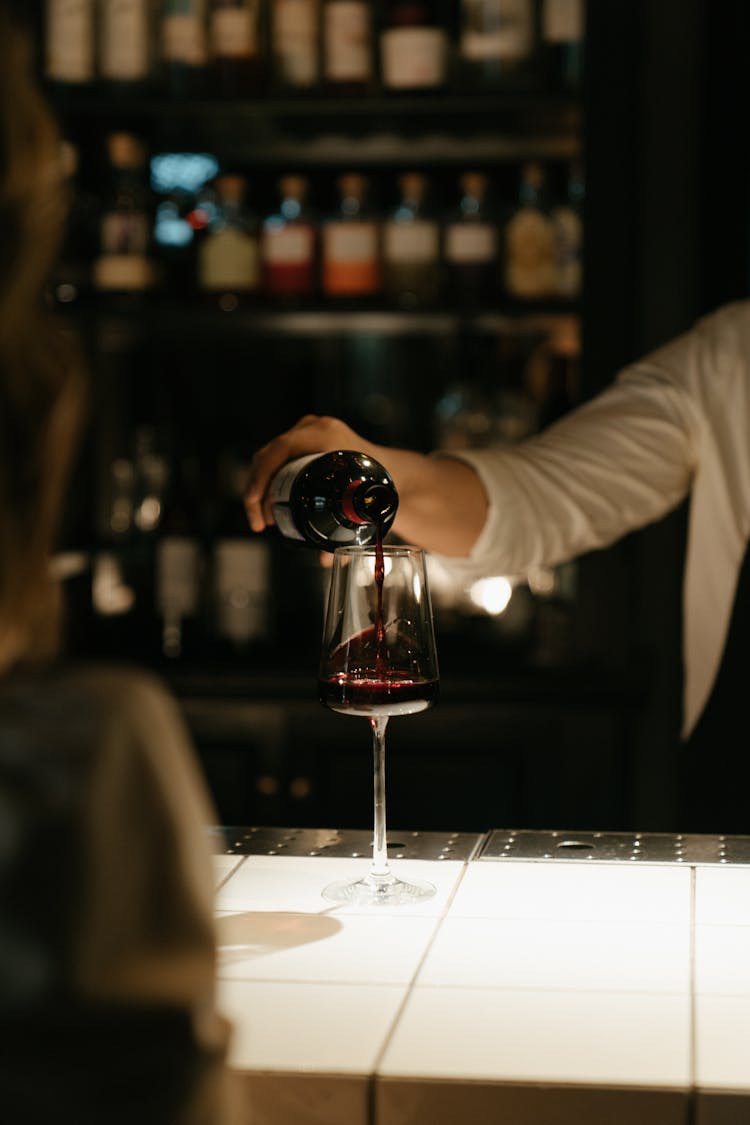 Person Pouring Wine On Wine Glass