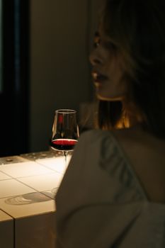 酒吧里，一名女子端着红酒，营造出优雅而略带忧郁的氛围