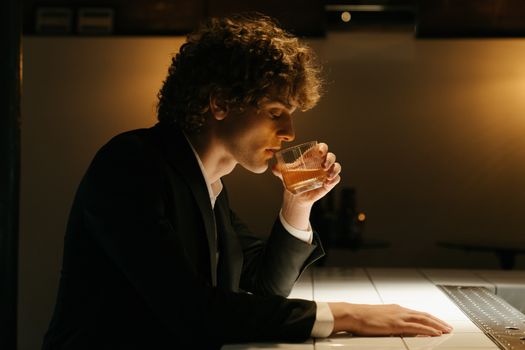 在一家优雅的酒吧里，一名西装革履的男子正喝着饮料，周围光线柔和