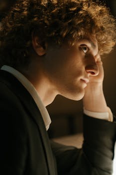 一位卷发、穿着西装的年轻人在酒吧里耐心等待的侧面图