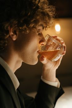 酒吧里，一名西装革履的时尚男子正喝着威士忌，气氛热烈