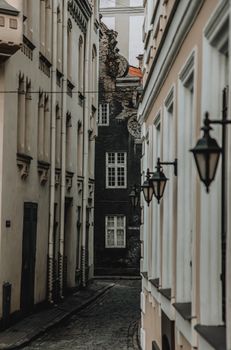 Cobblestone narrow side street between white apartment buildings in old city district in daylight