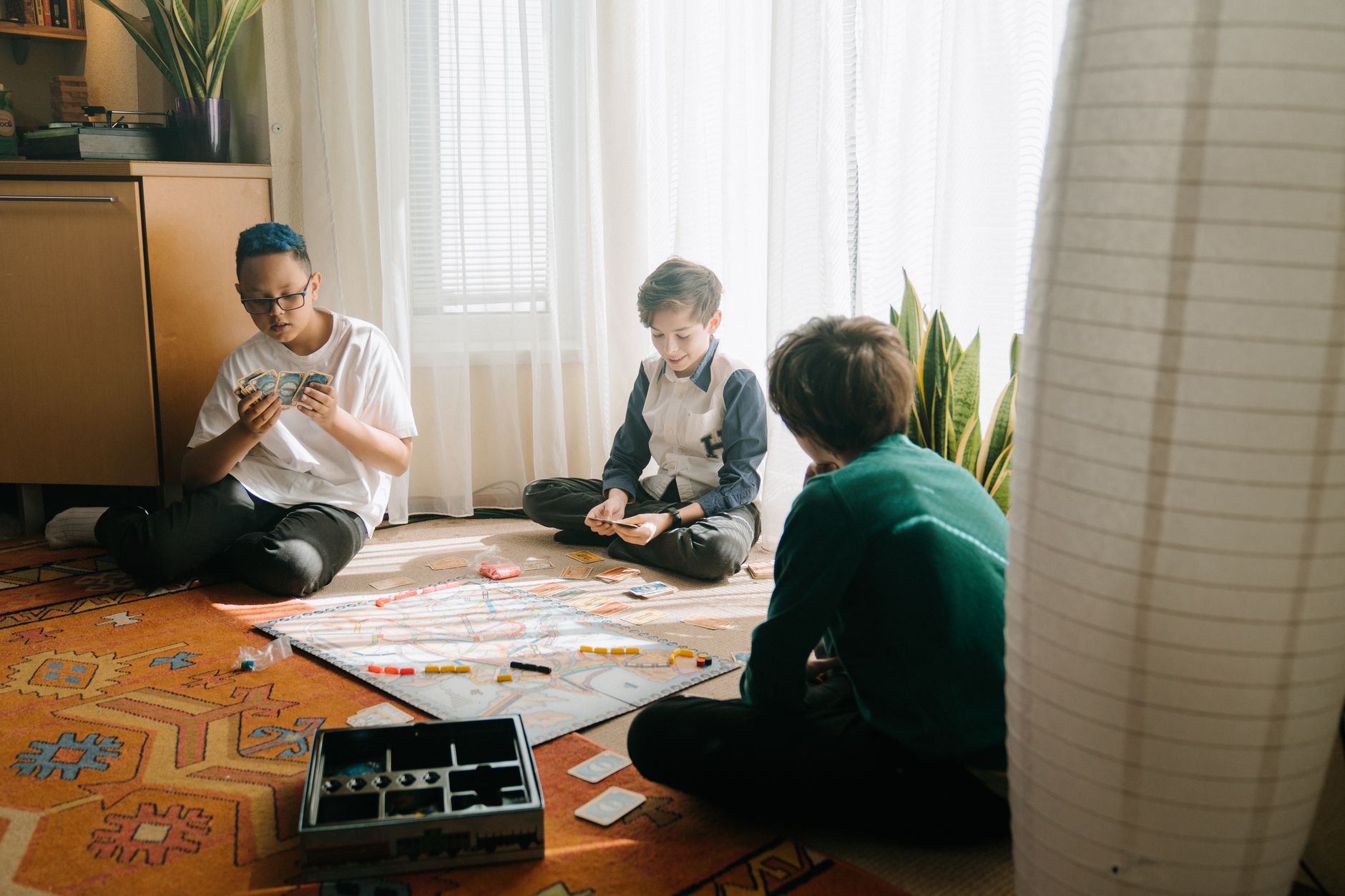 Three boys playing a strategic board game in a cozy indoor setting, emphasizing friendship and fun.