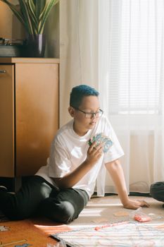 一个男孩坐在室内，专注地下着棋盘游戏，他有一头彩色的头发