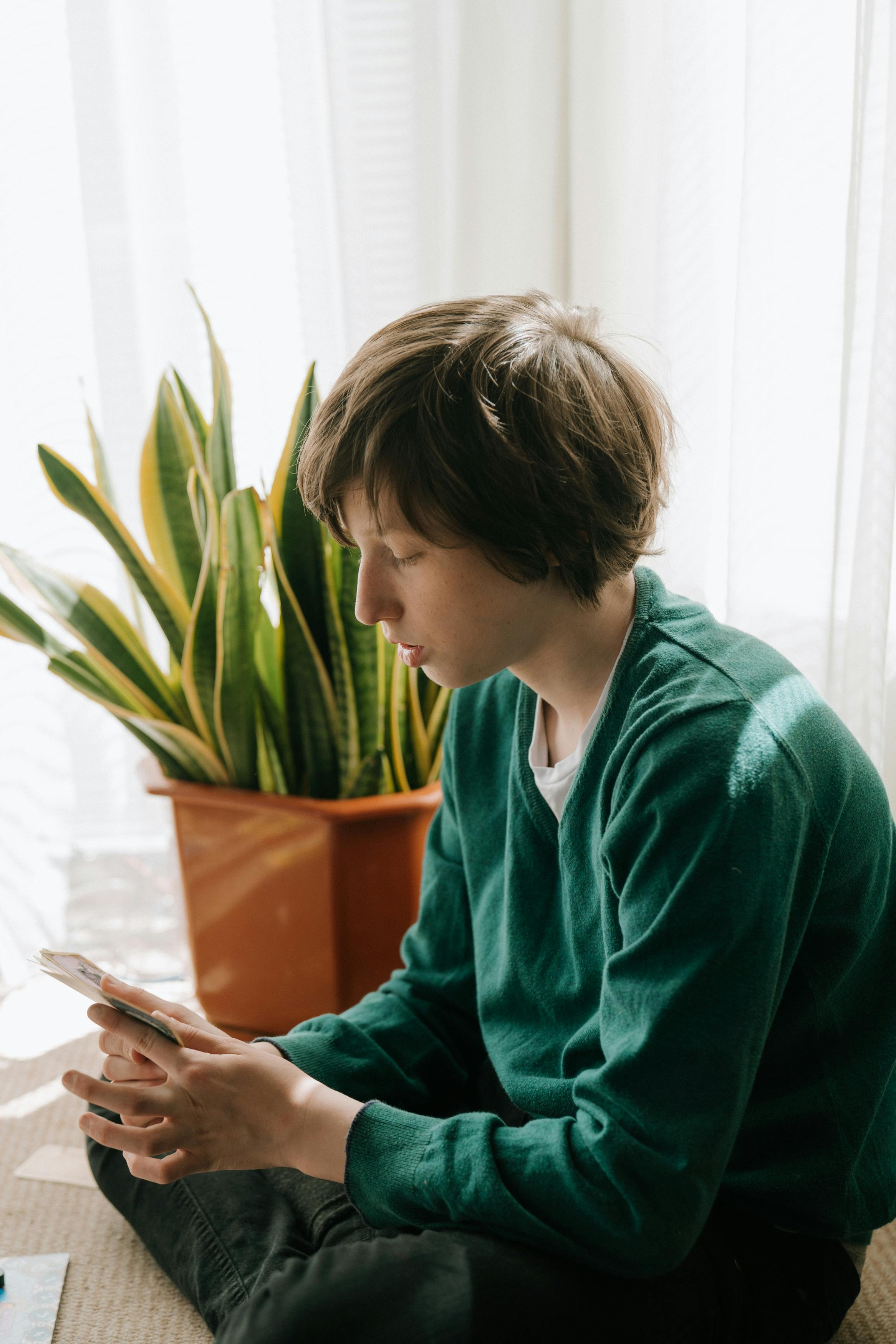 boy in green sweater holding pen