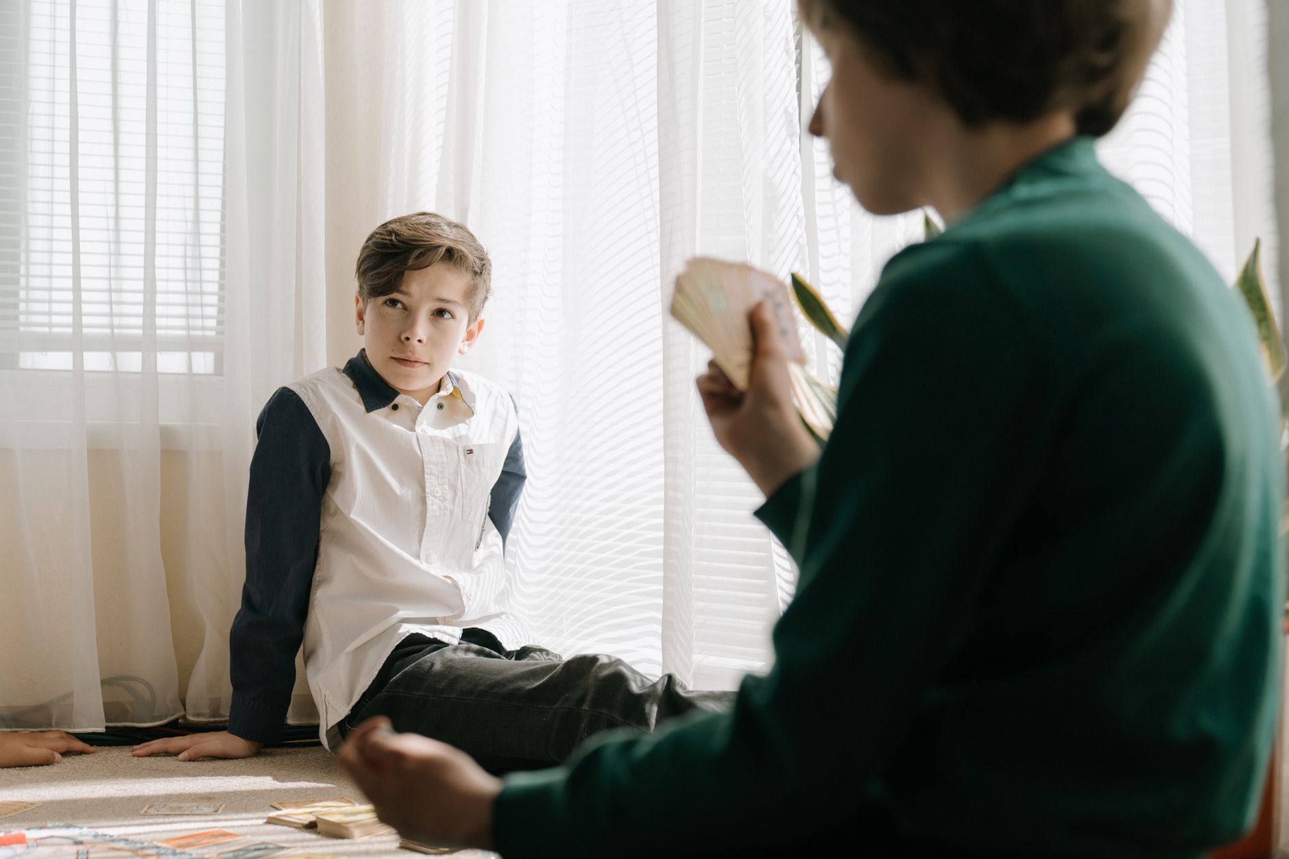 Two kids engaging in a card game indoors, enjoying leisure time and strategic gameplay.