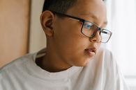 一个戴眼镜的小男孩在室内若有所思地凝视着肖像