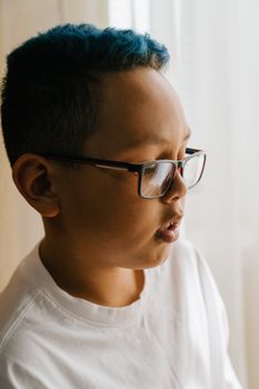 室内自然光下，一个蓝发戴眼镜的小男孩侧面肖像