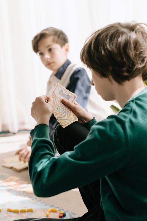 Boy in Green Sweater Holding Book Beside Boy in Black and White Striped Shirt