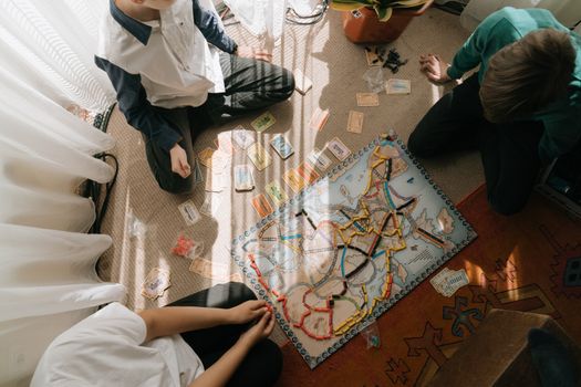 A group of children playing a board game indoors, enjoying leisure time together.