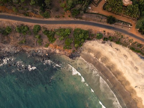 Free Aerial shot of coastal road and beach in Neware, India with waves and greenery. Stock Photo