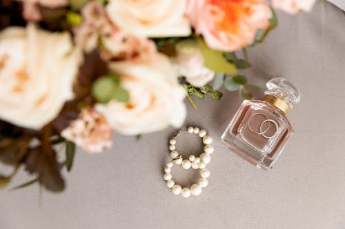 Flowers Beside Clear Glass Bottle With Engagement Rings