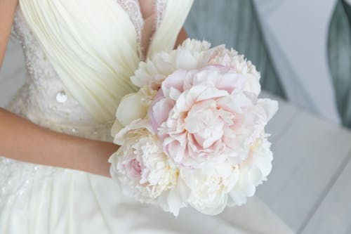 Woman in White Wedding Dress Holding a Flower Bouquet