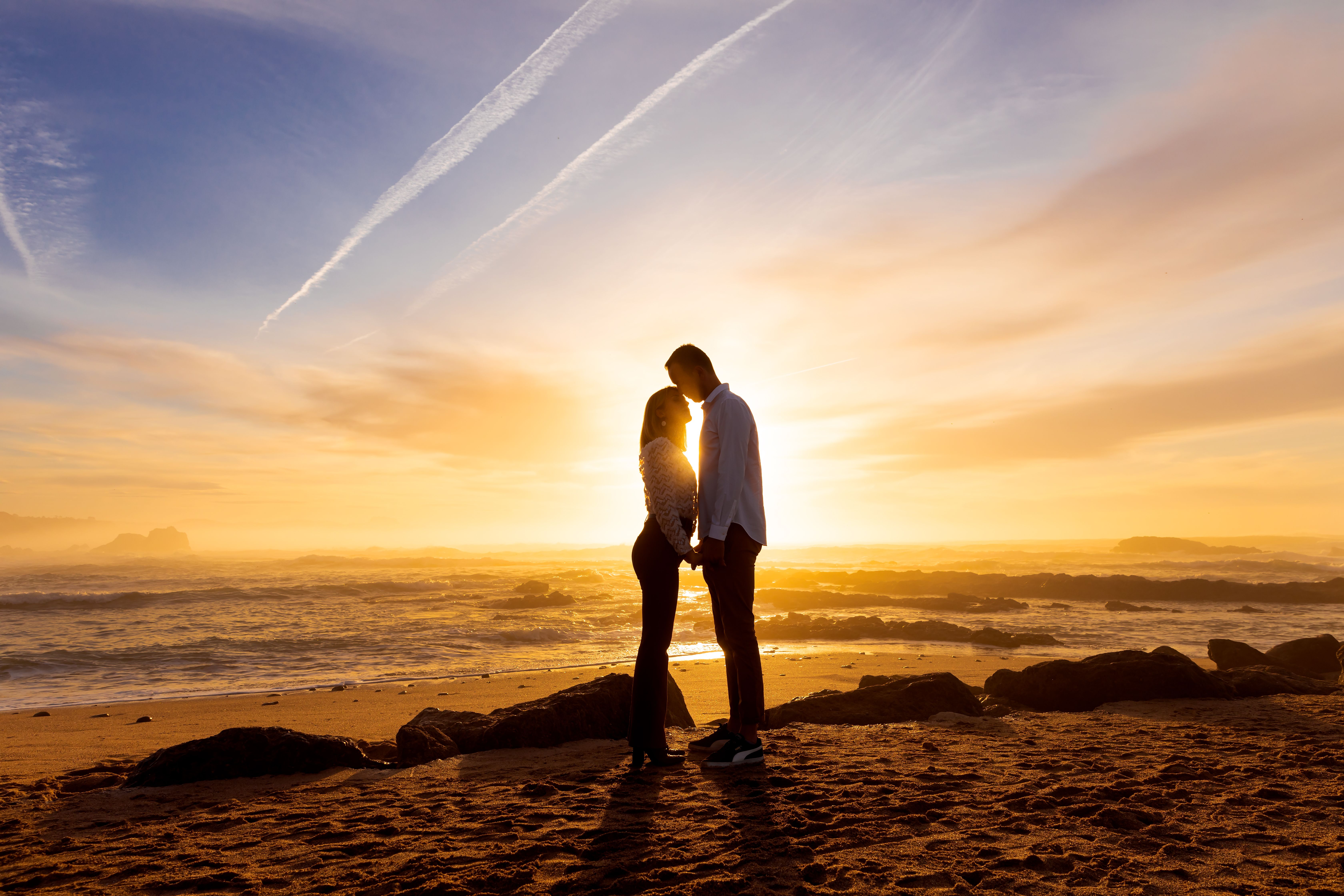 A Romantic Couple Standing on Seashore during Sunset · Free Stock Photo