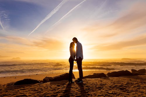 A Romantic Couple Standing on Seashore during Sunset