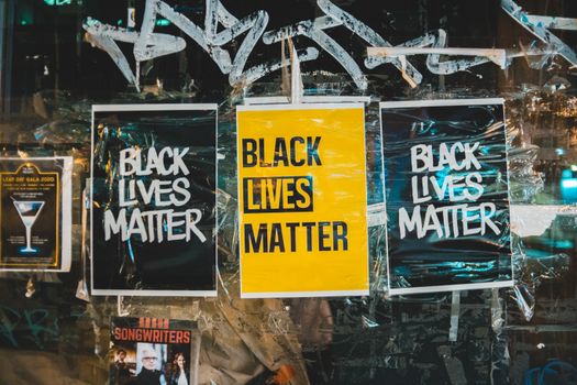 Slogan Black Lives Matter on small rectangular paper sheets on surface of painted glass