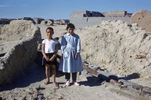 Free Two smiling children standing in a desert village, showcasing innocence and playfulness. Stock Photo