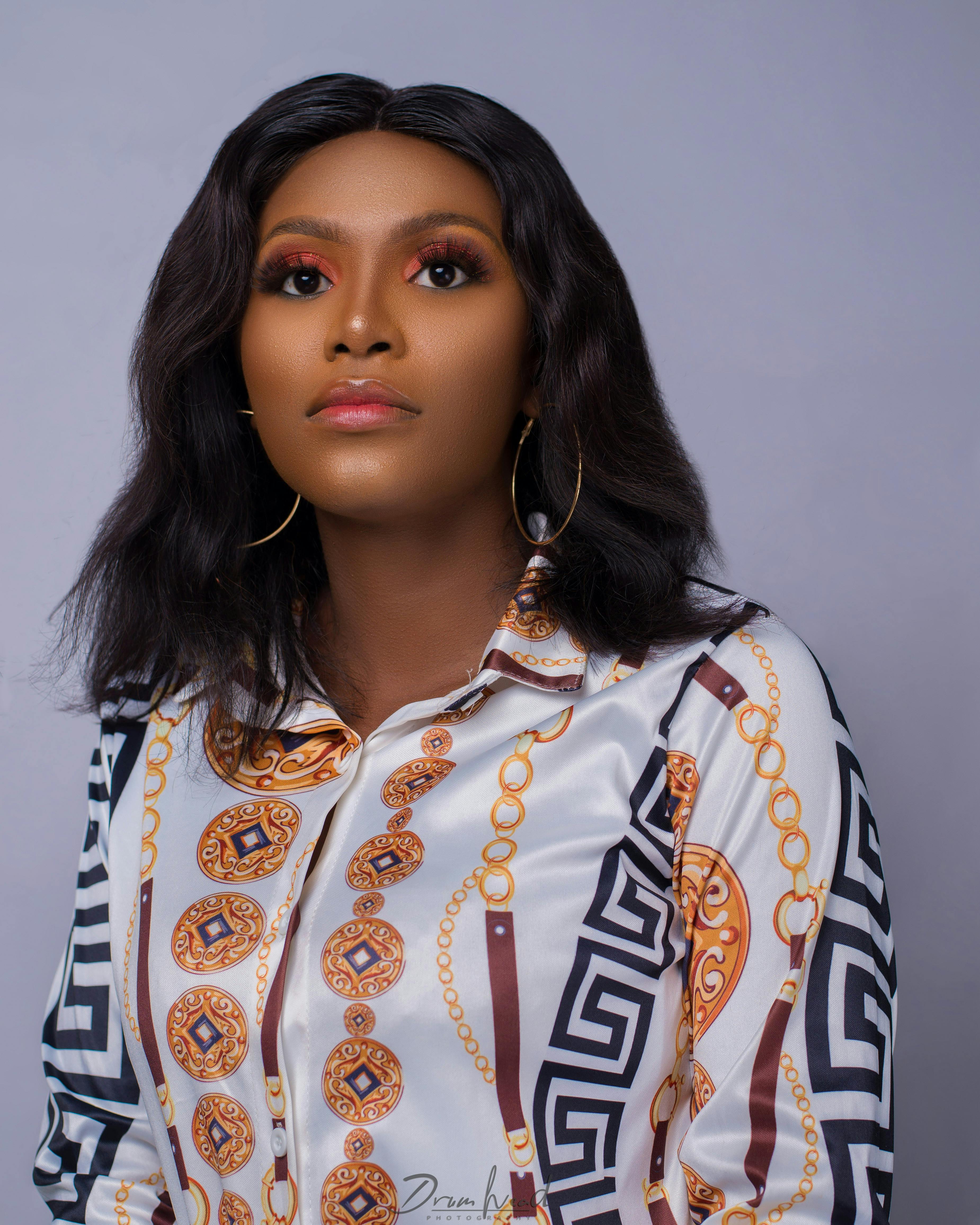 Close-up studio portrait of a stylish woman wearing designer attire, showcasing elegance.