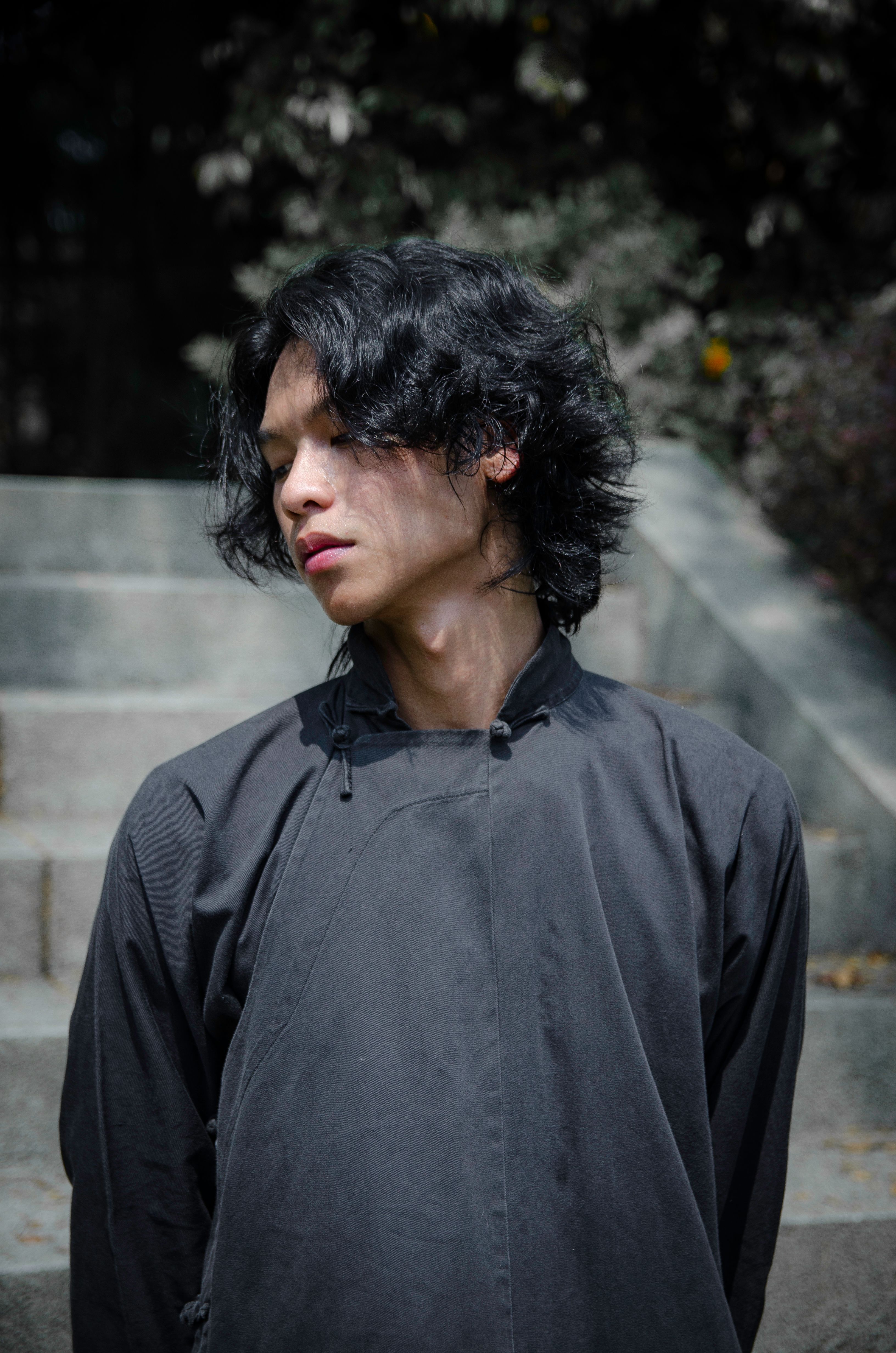 A young man standing on stairs in Malaysia, looking down thoughtfully.