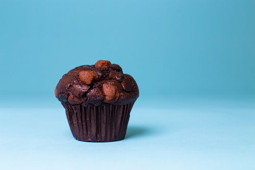 Free Chocolate muffin with chocolate chips against a simple blue backdrop, showcasing tasty indulgence. Stock Photo