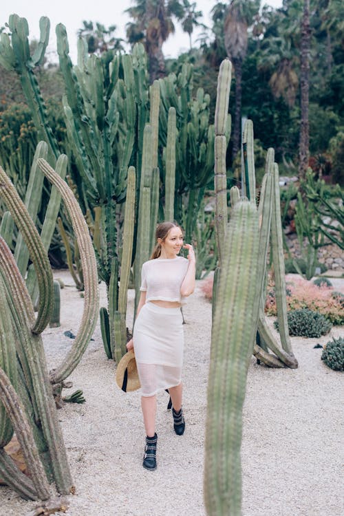 Woman in White Top and Skirt Standing Beside Green Cactus