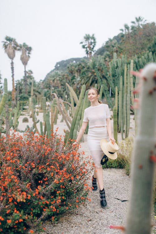 Woman in White Dress Standing on Pathway Surrounded by Green Plants