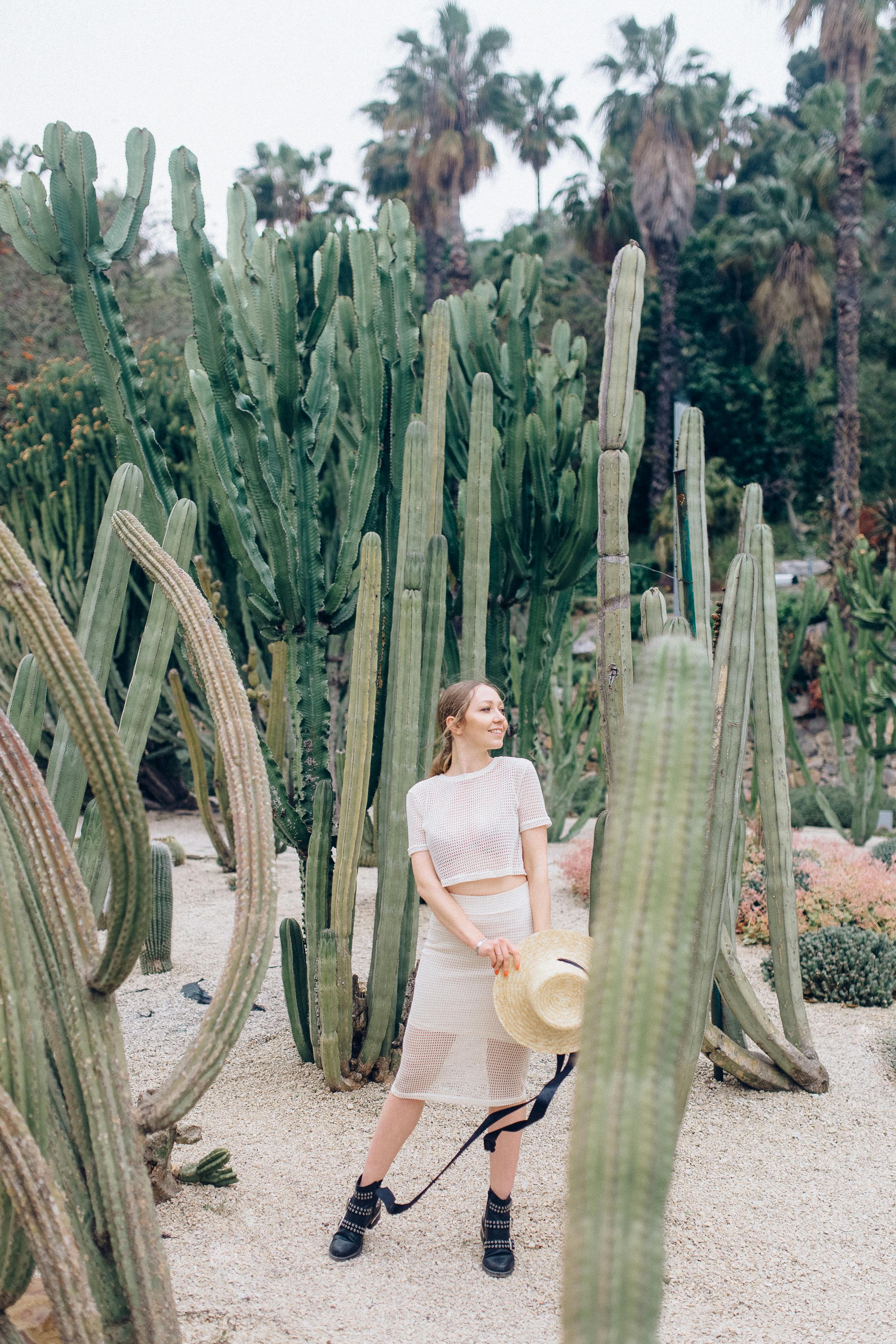 在沙漠花园里，一个戴着草帽的女人被高大的仙人掌包围着